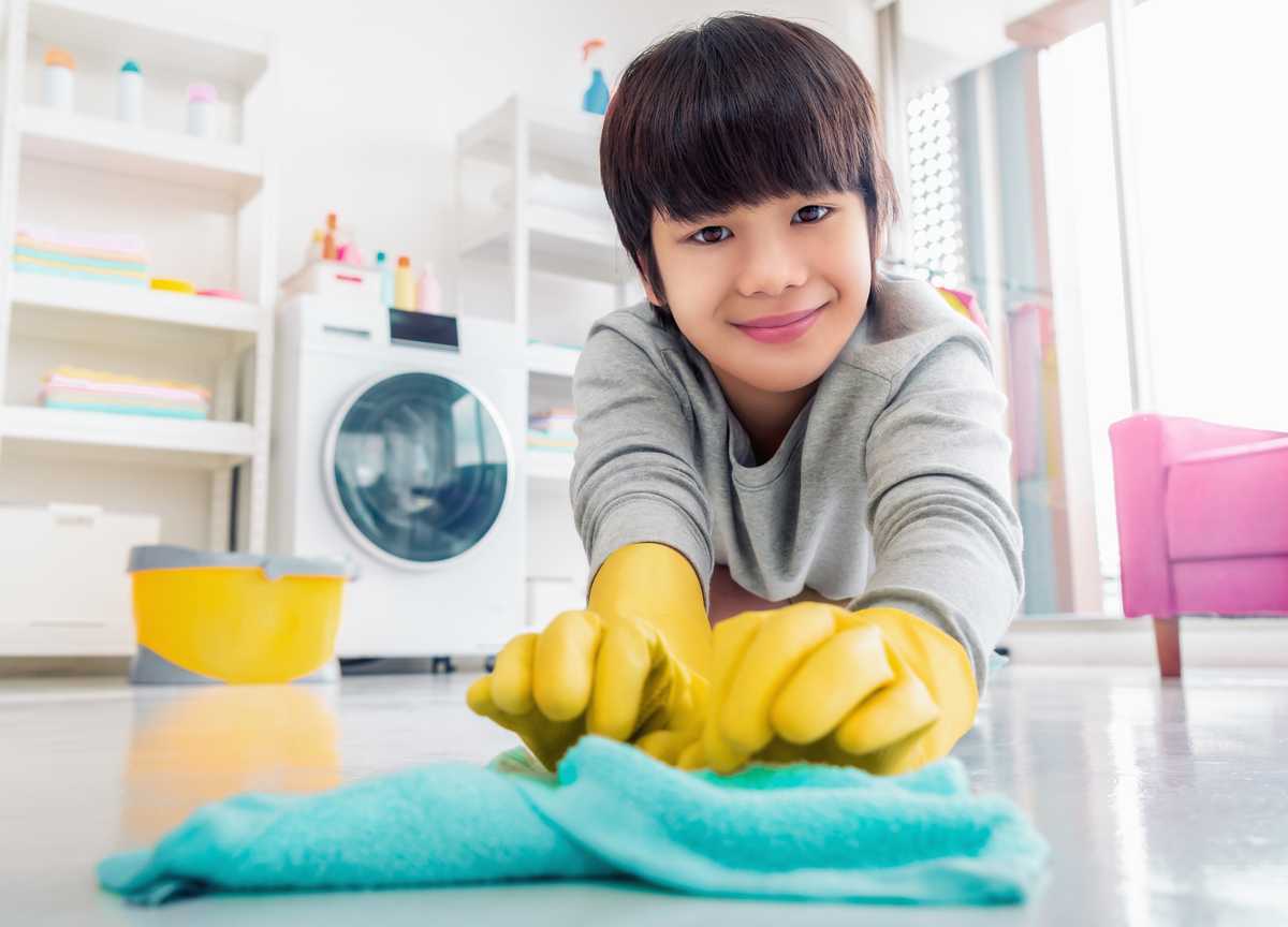 A smiling young boy cleaning the floor