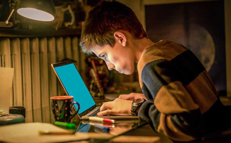 A young boy working intently on his laptop
