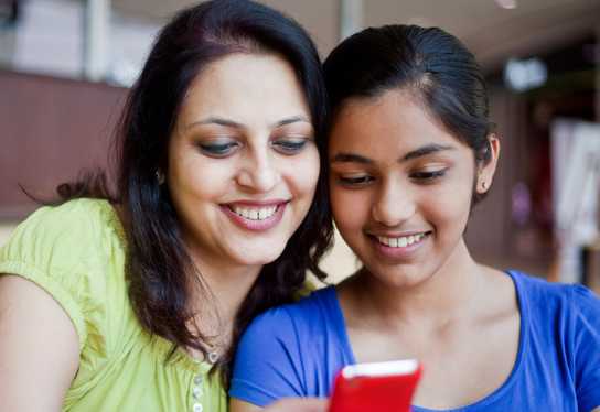Mother and daughter looking at the daughter's smartphone showing the Till Financial app