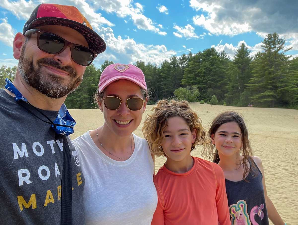 A family of four hiking in the woods and smiling